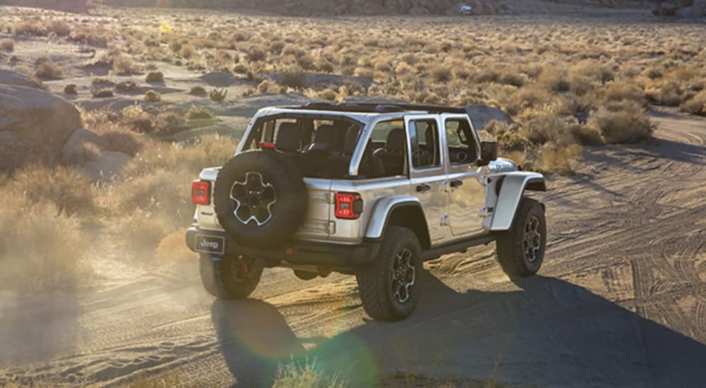 A silver 2023 Jeep Wrangler is shown from the rear off-roading.