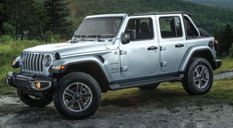 A grey 2023 Jeep Wrangler is shown from the side parked on a dirt road.