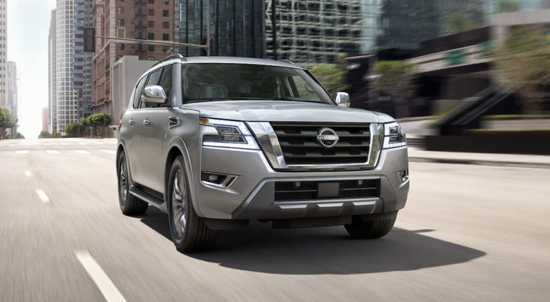 A grey 2023 Nissan Armada is shown from the front driving through a city.