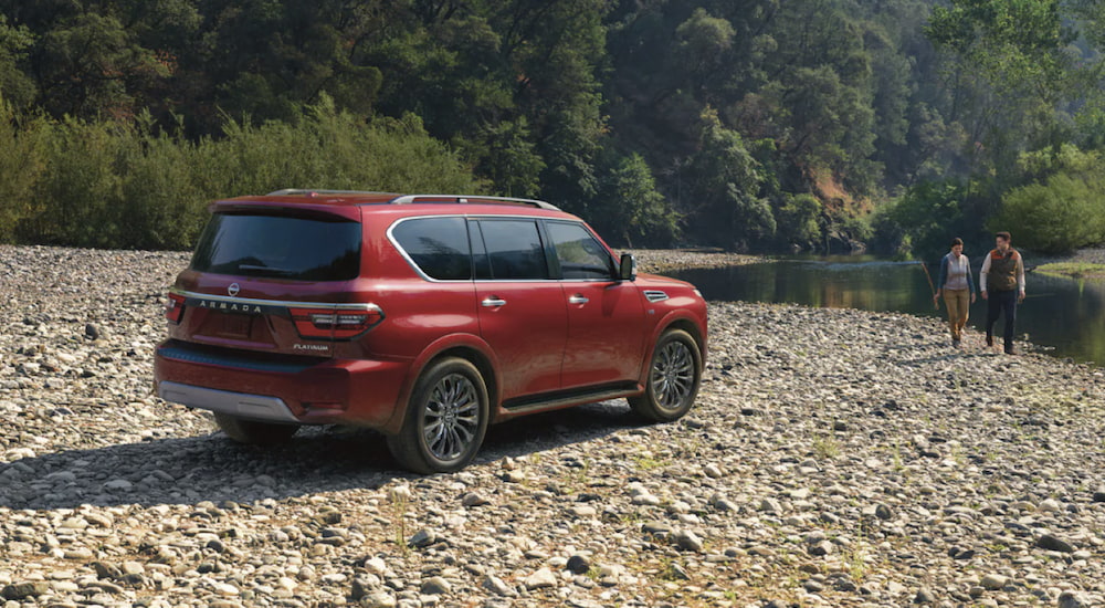 A red 2023 Nissan Armada is shown from the side parked next to a river.