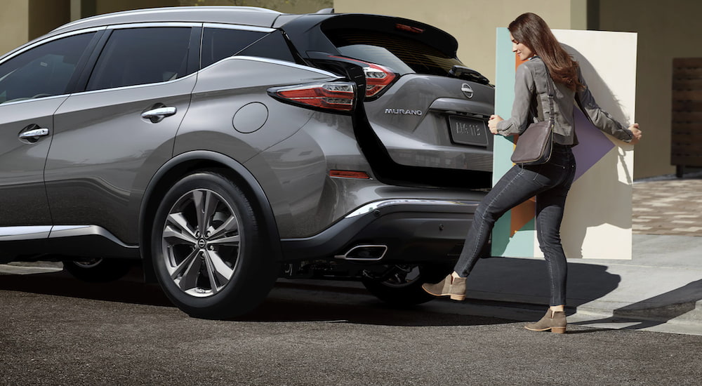 A person is shown opening the lift gate on a grey 2023 Nissan Murano.
