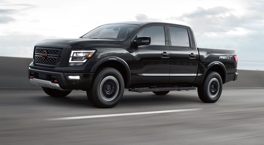 A black 2023 Nissan Titan is shown from the side driving on a highway.
