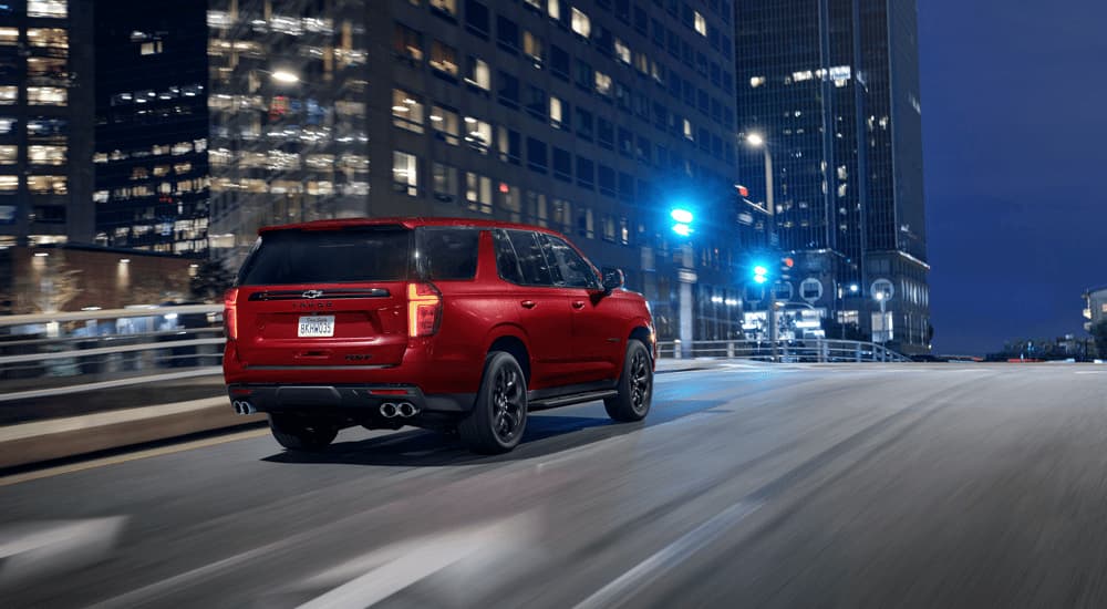 A red 2023 Chevy Tahoe RST Performance is shown from the rear driving on a city highway.