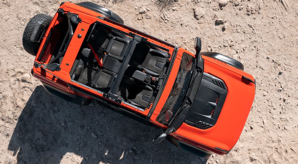 A red 2022 Ford Bronco Raptor is shown from above on a dirt road after leaving a Ford Bronco dealership.