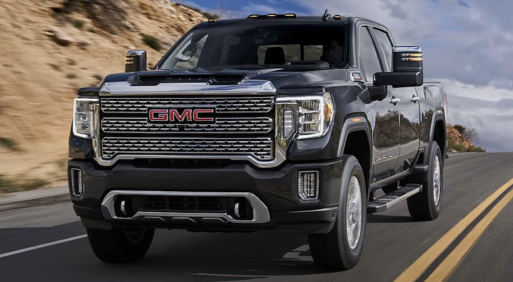 A black 2023 GMC Sierra 2500 HD Denali is shown from the front driving on an open road after visiting a GMC Sierra 1500 dealer.