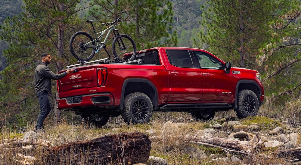 A red 2023 GMC Sierra 1500 AT4X is shown in the woods after leaving a GMC Sierra dealer.