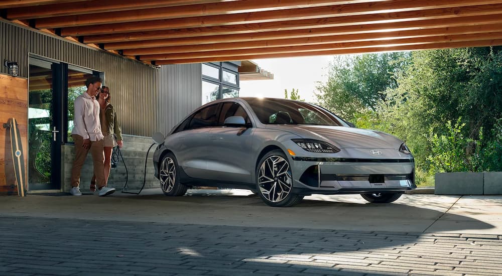 A silver 2023 Hyundai Ioniq 6 is shown charging in a driveway.