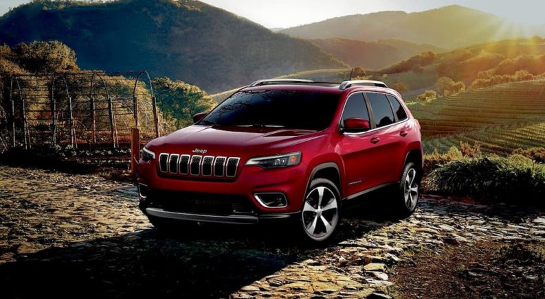 A popular Jeep Cherokee for sale, a red 2019 Jeep Cherokee, is shown parked in front of a mountain.