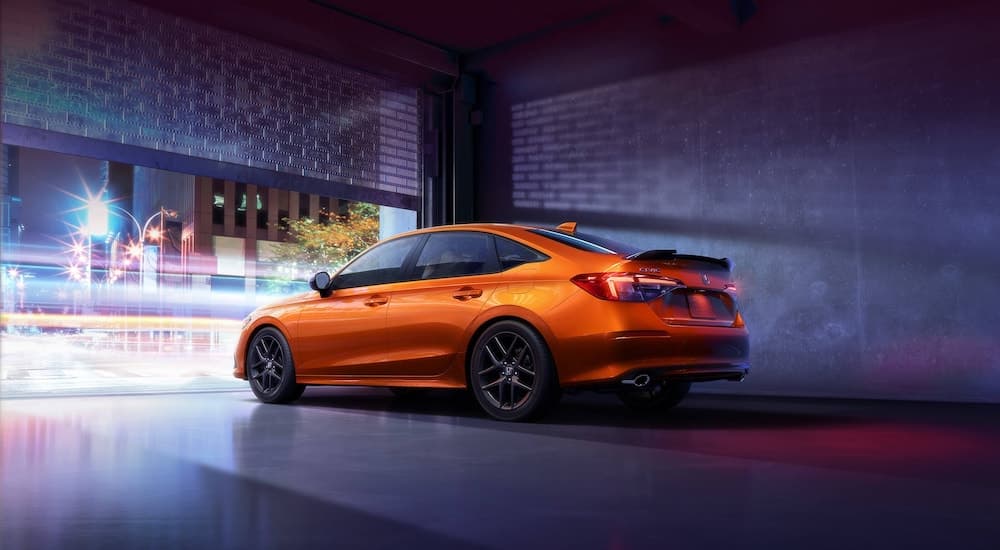 An orange 2022 Honda Civic SI is shown from the rear at an angle after leaving a Honda dealer.