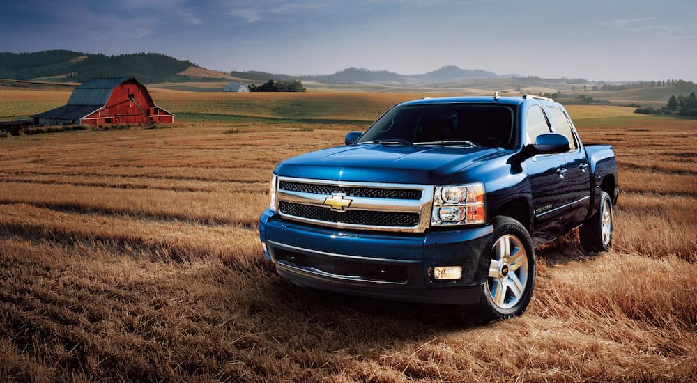 A blue 2007 Chevy Silverado 1500 is shown from the side parked in a field after leaving a used truck dealership.
