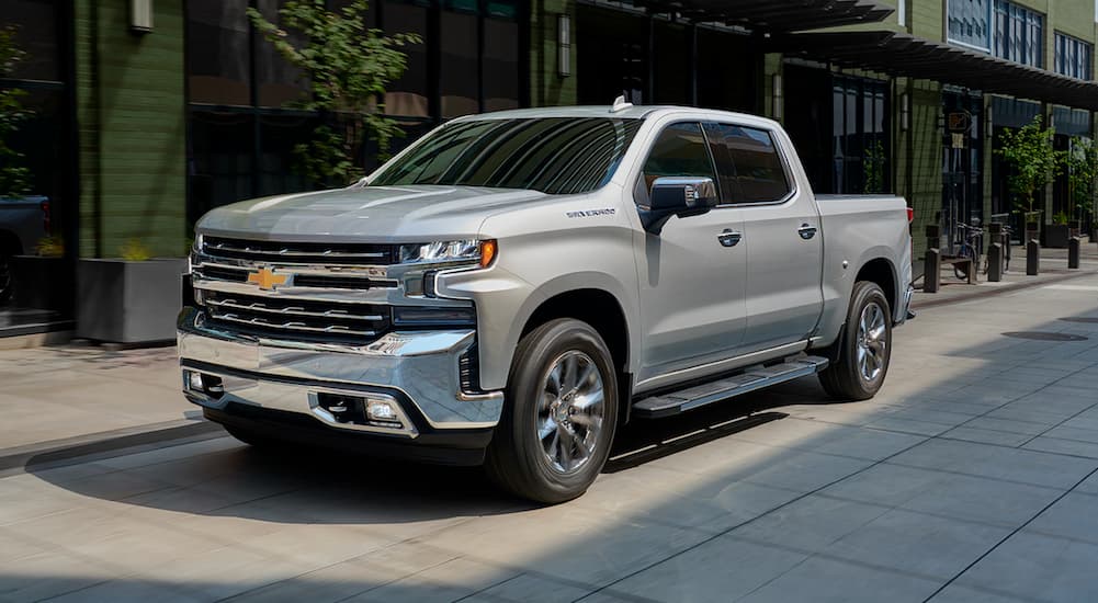 A silver 2019 Chevy Silverado 1500 is shown parked on the side of a city street after leaving a used car dealer near you.