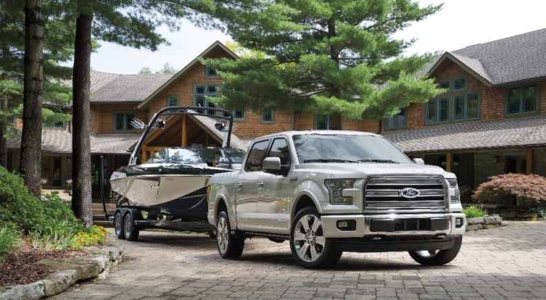 A white 2016 Ford F-150 Limited is shown towing a boat after leaving a used truck dealer.