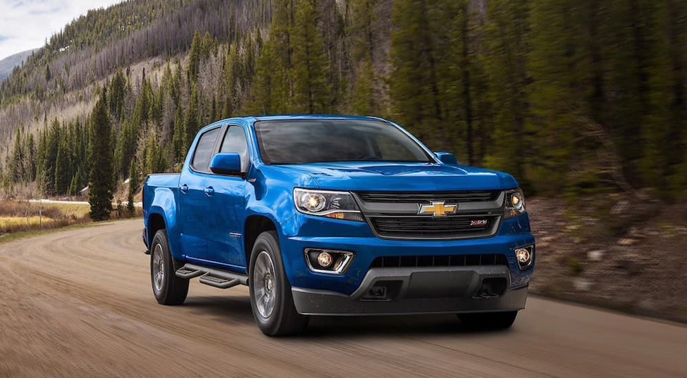 A blue 2020 Chevy Colorado Z71 is shown driving on a dirt road.