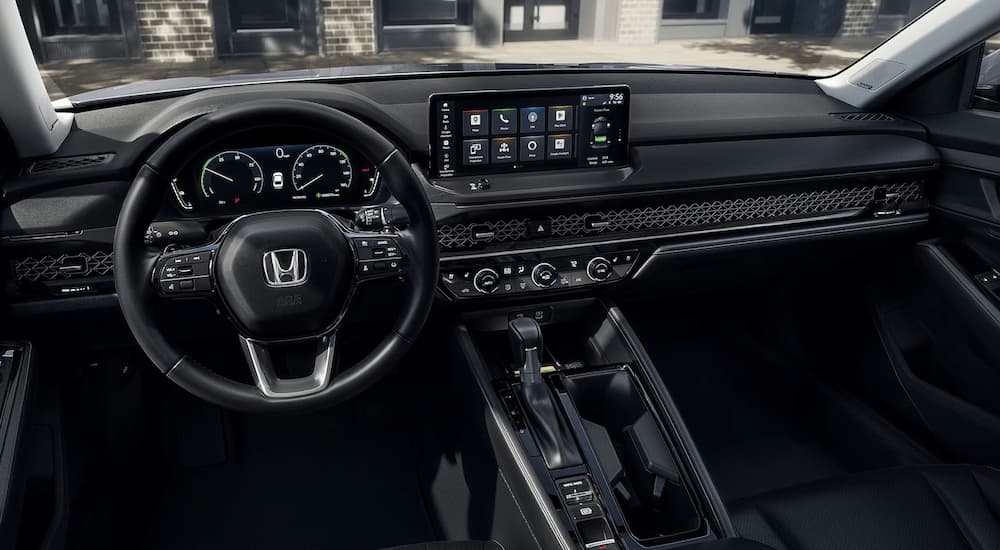 The black interior of a 2023 Honda Accord Touring Hybrid shows the infotainment screen and center console.