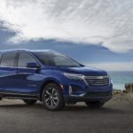 A blue 2023 Chevy Equinox Premier is shown from the side during a 2023 Chevy Equinox vs 2023 Nissan Rogue comparison.
