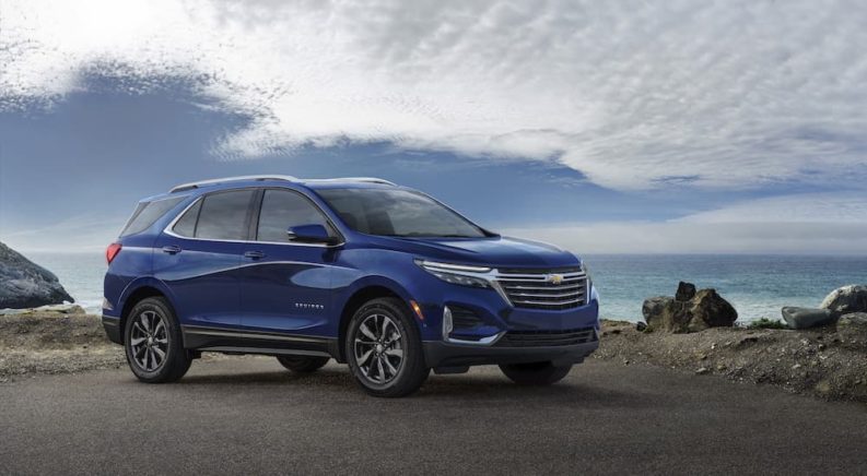 A blue 2023 Chevy Equinox Premier is shown from the side during a 2023 Chevy Equinox vs 2023 Nissan Rogue comparison.