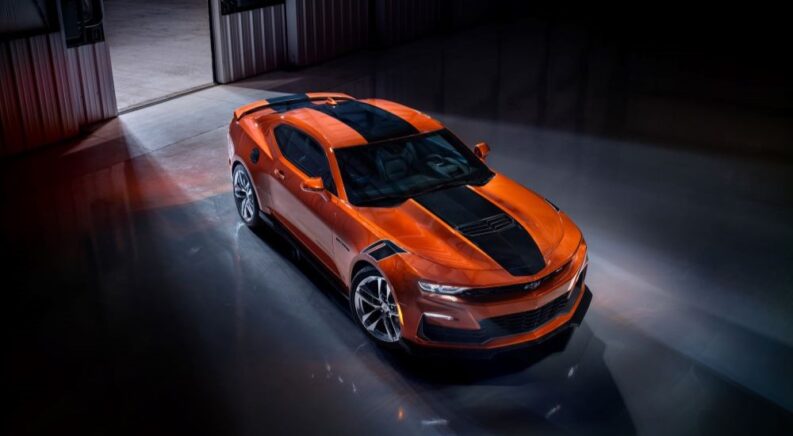An orange 2023 Chevy Camaro SS is shown parked in a warehouse.