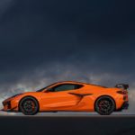 An orange 2023 Chevy Corvette Stingray Z06 is shown from the side on a cloudy day.