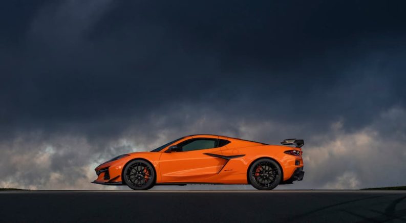 An orange 2023 Chevy Corvette Stingray Z06 is shown from the side on a cloudy day.