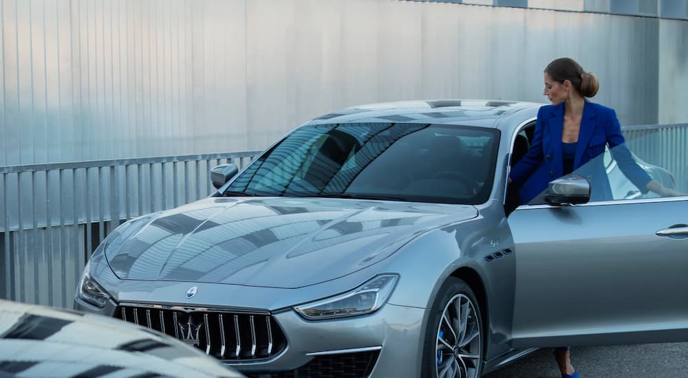 A woman is shown getting into the driver's seat of a silver 2023 Maserati Ghibli.