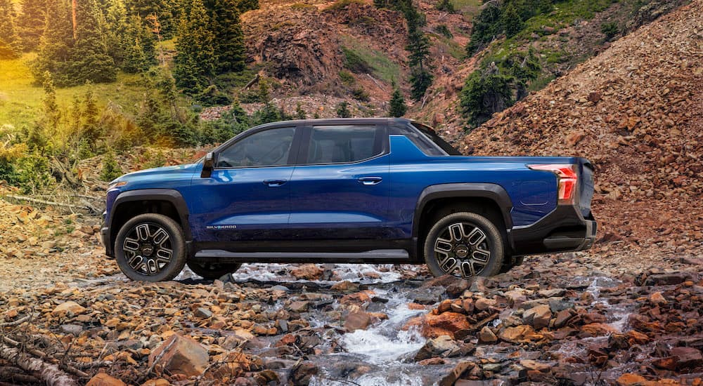 A blue 2024 Chevy Silverado EV RST is shown from the side while off-road.