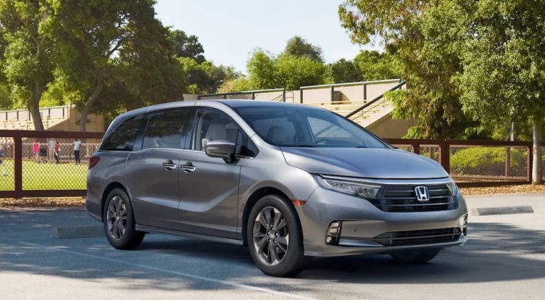 A silver 2023 Honda Odyssey Elite is shown parked next to a sports field after leaving a Honda dealer.