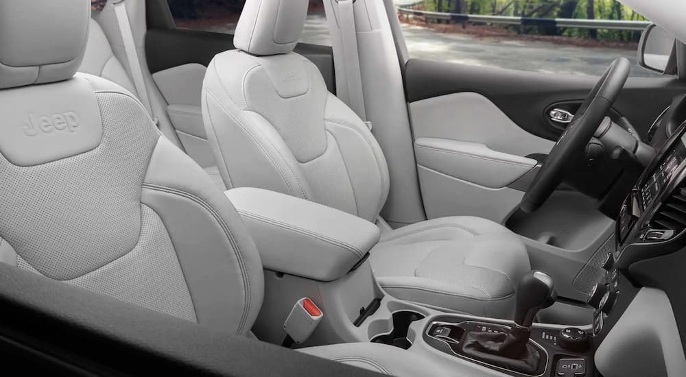 They grey interior of a 2022 Jeep Cherokee for sale shows the front seat and center console.