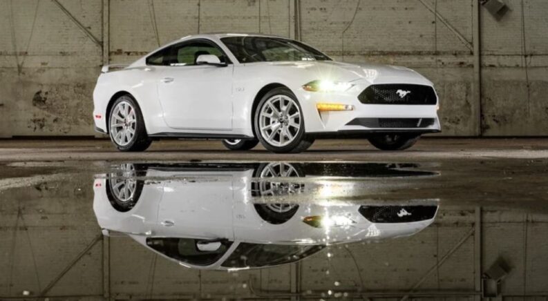 A white 2023 Ford Mustang GT is shown parked near a puddle.