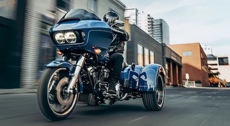 A blue 2023 Harley-Davidson Road Glide 3 is shown driving on a street.
