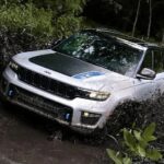 A white 2023 Jeep Grand Cherokee Trailhawk 4xe is shown off-roading.