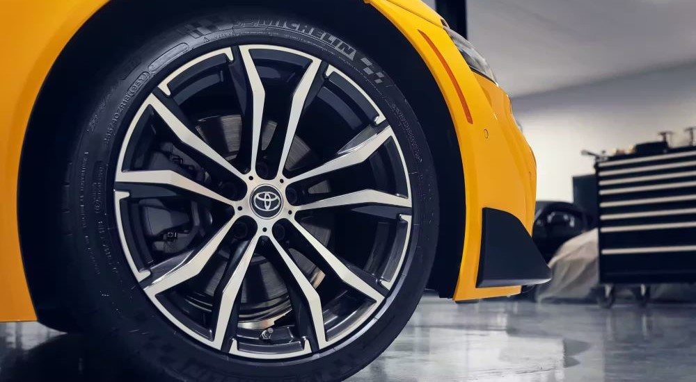 A close up shows the front passenger wheel on a yellow 2023 Toyota GR Supra.