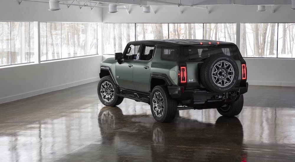 A green 2024 GMC Hummer EV is shown from the rear at an angle.