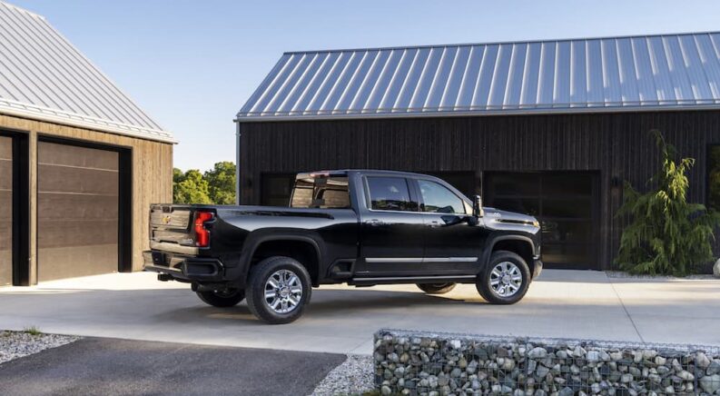 A black 2024 Chevy Silverado 2500 HD is shown from the side after leaving a dealer that has Chevy trucks for sale.