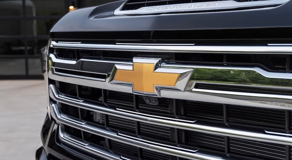 A close up of the grille on a black 2024 Chevy Silverado 2500 HD is shown.