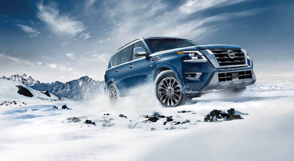 A blue 2023 Nissan Armada is shown driving on the snow.