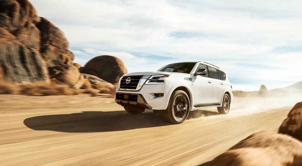 A white 2023 Nissan Armada is shown driving on a dirt road.