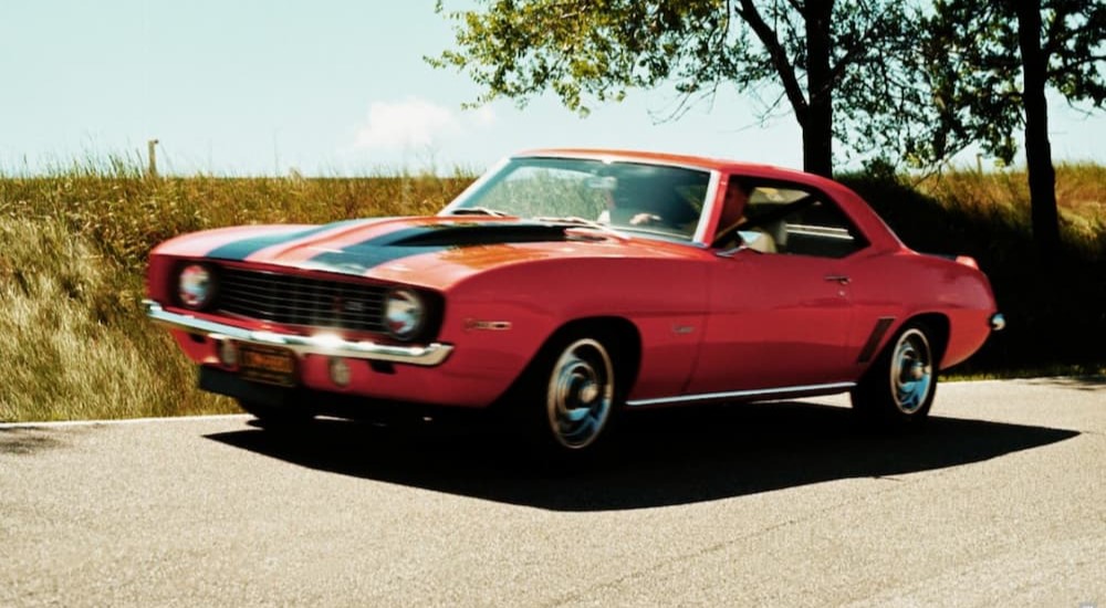 A 1969 Chevy Camaro Z28 is shown driving on a road.