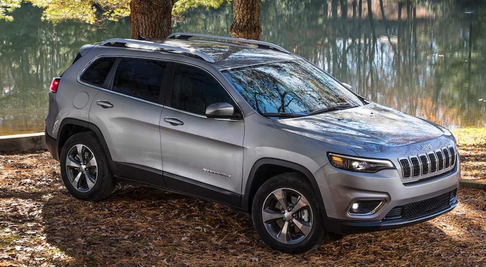 A silver 2020 Jeep Cherokee is shown parked beside a lake.