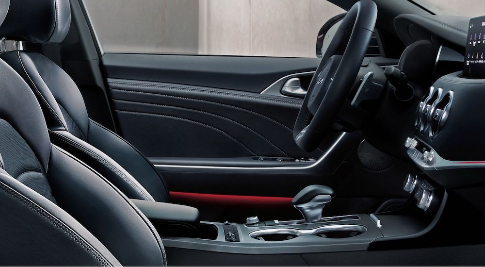 The black interior of a 2023 Kia Stinger is shown from the passenger door opening.