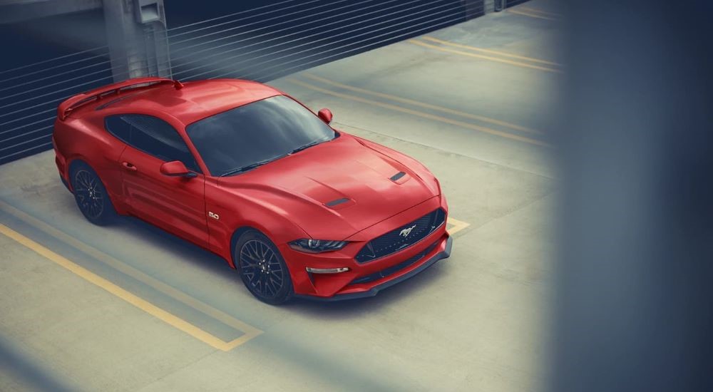 A red 2023 Ford Mustang is shown parked inside of a parking garage.