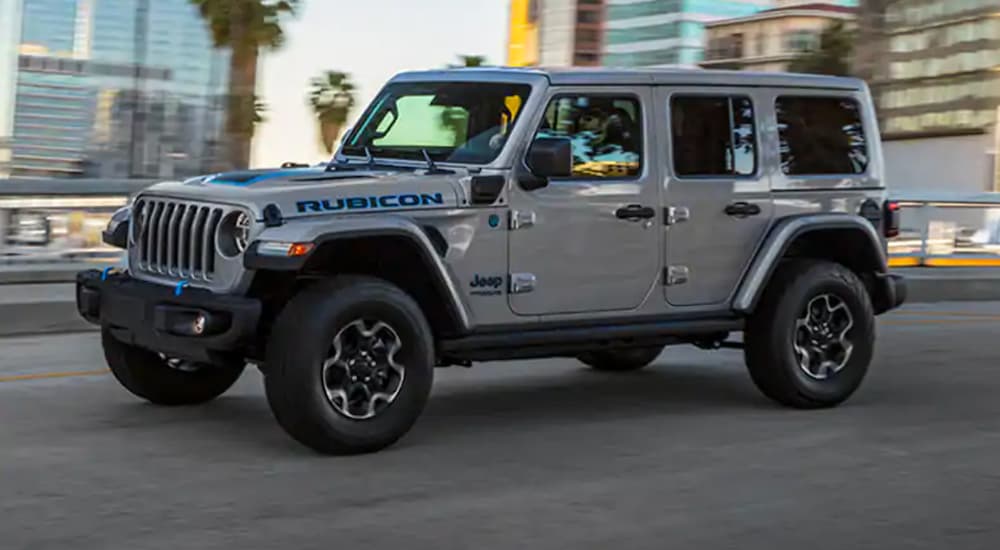 A gray 2021 Jeep Wrangler 4xe Rubicon is shown driving on a city street after looking at a used Jeep Wrangler for sale.