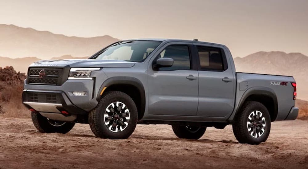 A grey 2023 Nissan Frontier Pro-4x is shown from the side while off-road during a 2023 Nissan Frontier vs 2023 Toyota Tacoma comparison.