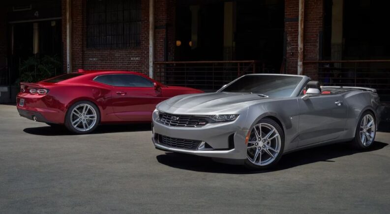 A red 2023 Chevy Camaro coupe and a silver 2023 Camaro convertible are parked next to each other.