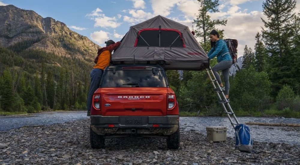A red 2023 Ford Bronco Sport is shown parked off-road with a roof tent.
