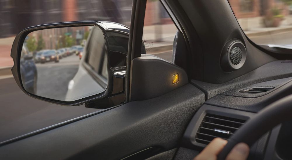 The interior driver's side window in the 2023 Honda Passport is shown with the blind spot indicator lit up. 