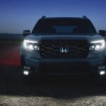 The front of a 2023 Honda Passport for sale is shown at night with the headlights on.