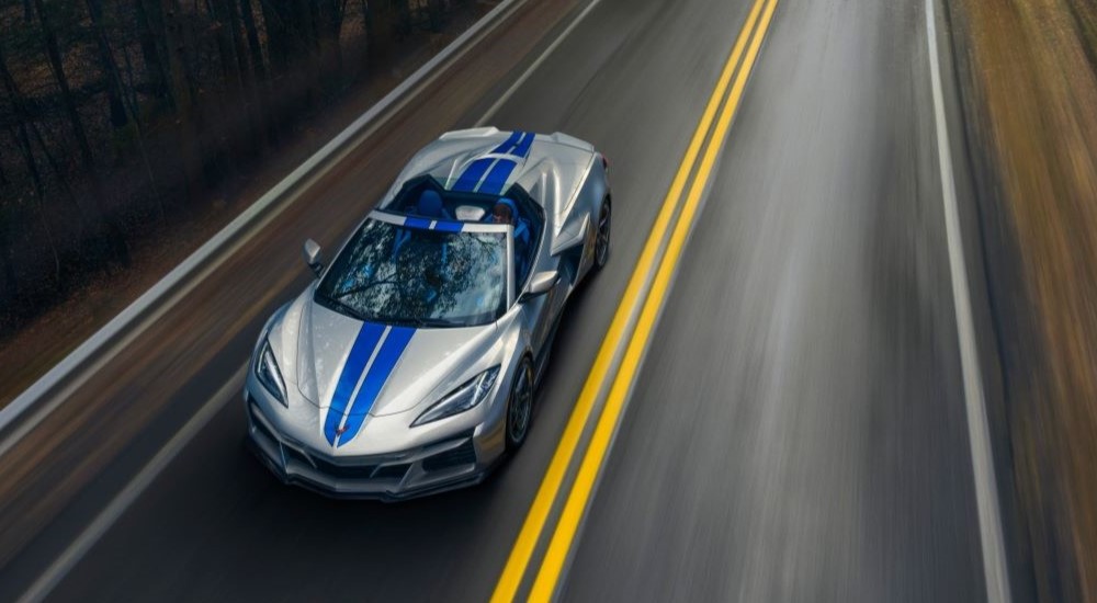 An aerial view of a silver 2024 Chevy Corvette E-Ray 3LZ is shown driving on a highway.