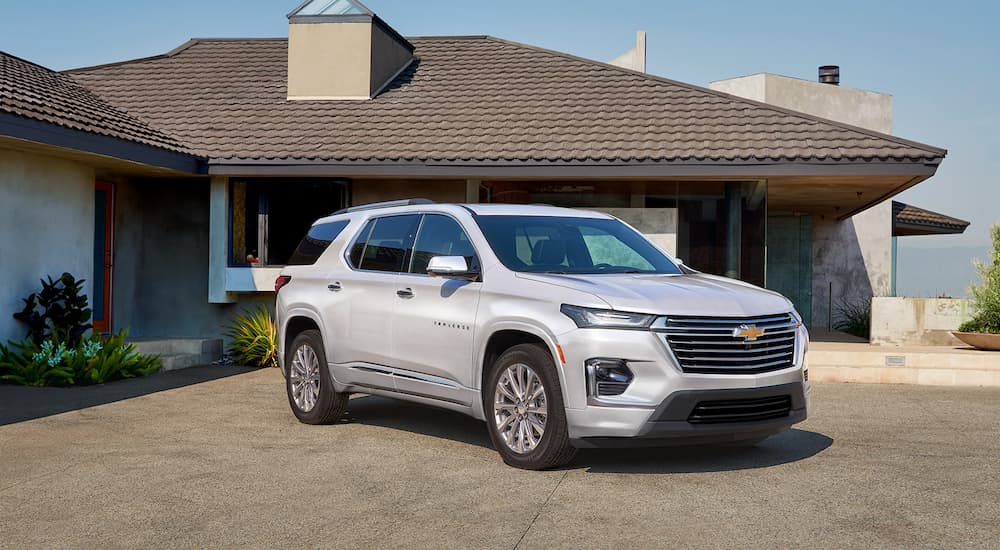 A silver 2023 Chevy Traverse is shown parked in front of a single story house.