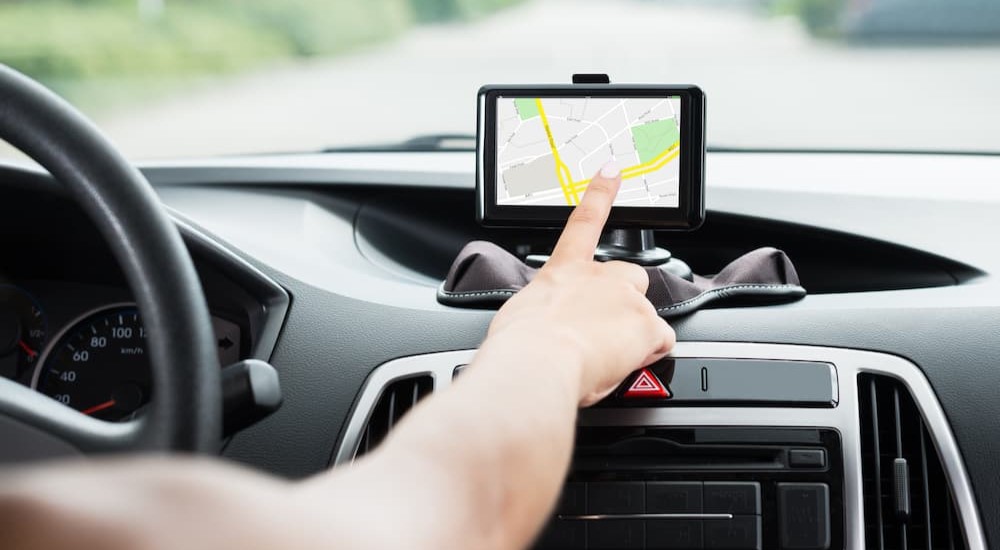 A hand is shown pressing on the screen of a GPS.