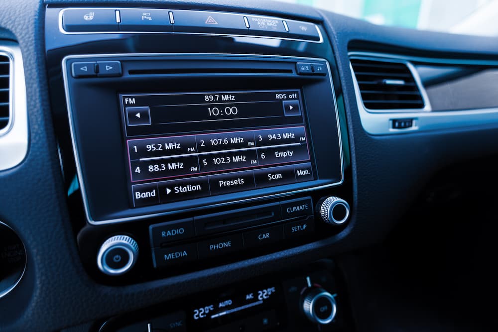 A touchscreen display on a radio is shown on a black dash.